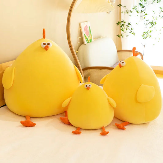Three yellow plush toys shaped like chickens on a light-colored surface.